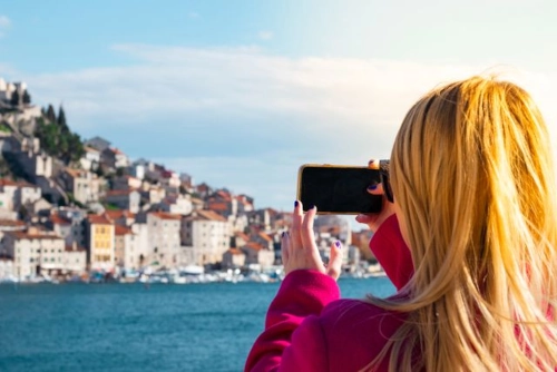 Kvinna fotograferar en stad vid vattnet i Kroatien.